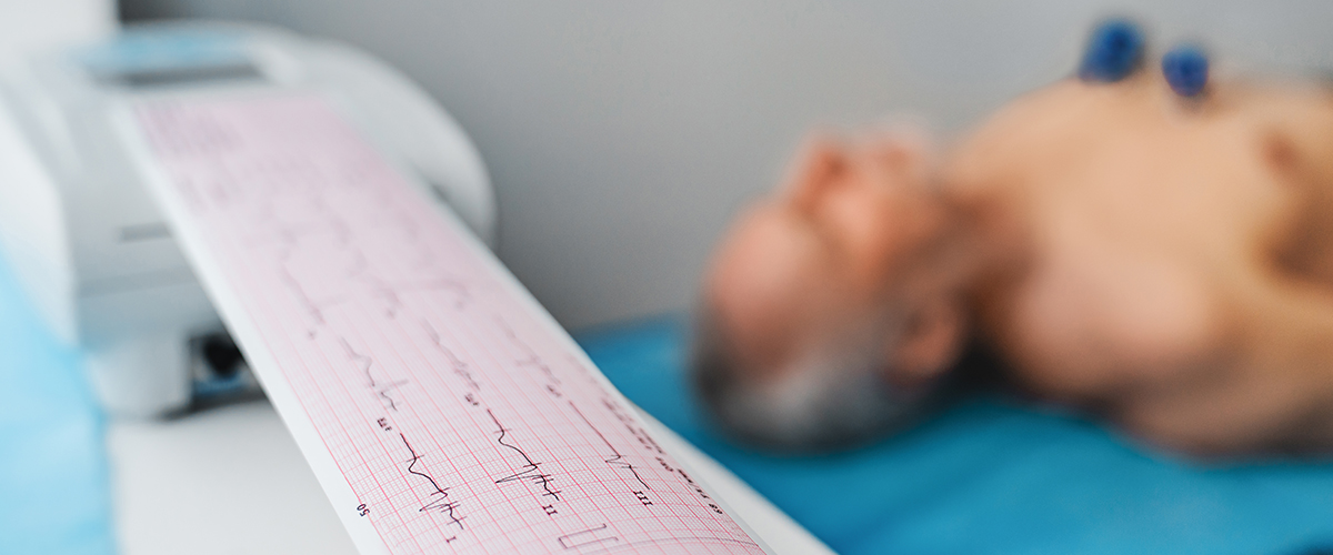 A man lying on the table, with a closeup of an ECG reading